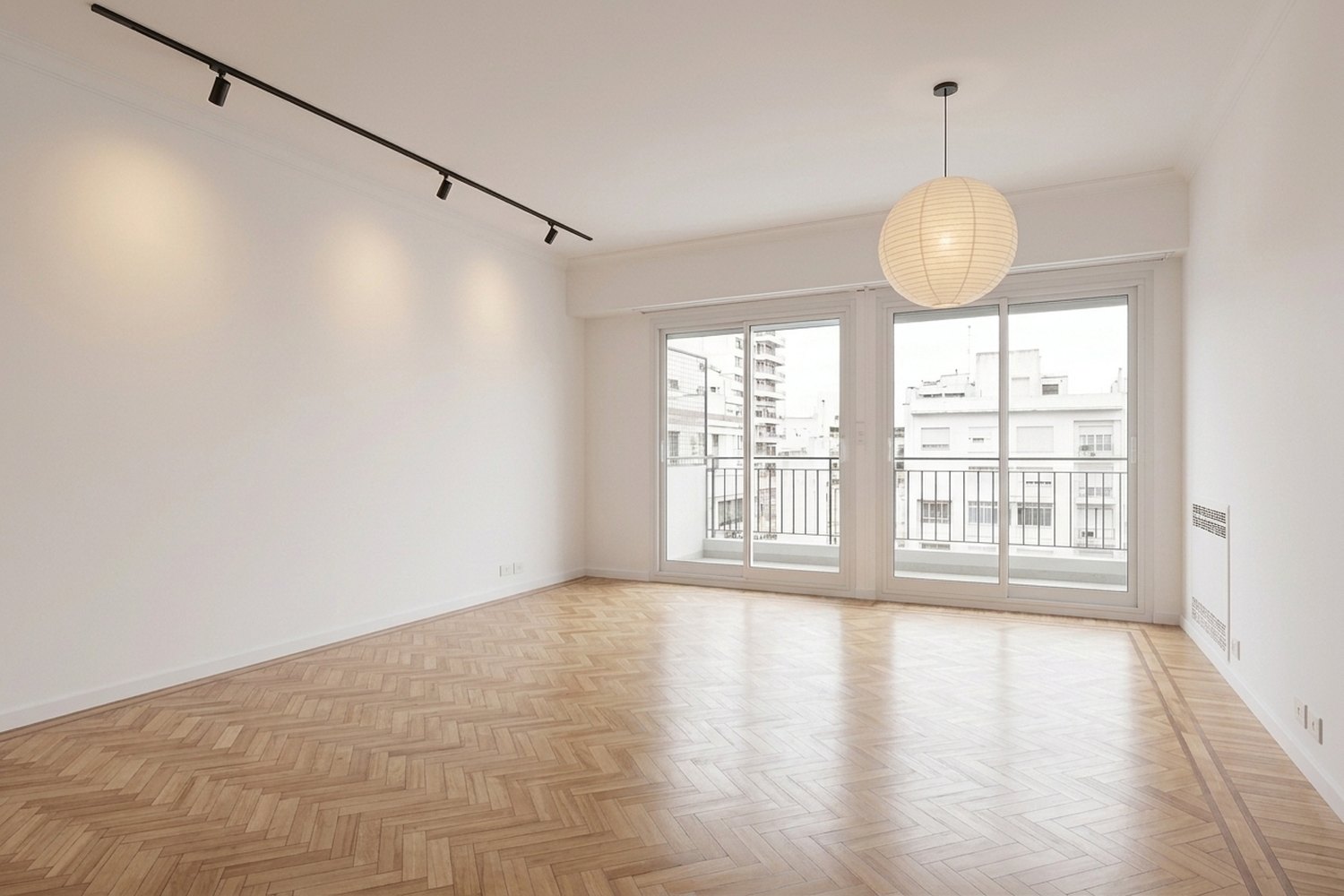 Living vacío con piso de parquet espiga y ventanales al balcón